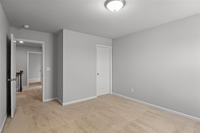 unfurnished bedroom featuring light carpet and baseboards