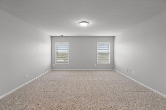 unfurnished room featuring light carpet, plenty of natural light, and baseboards