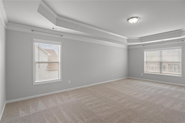 empty room with a tray ceiling, carpet flooring, and crown molding