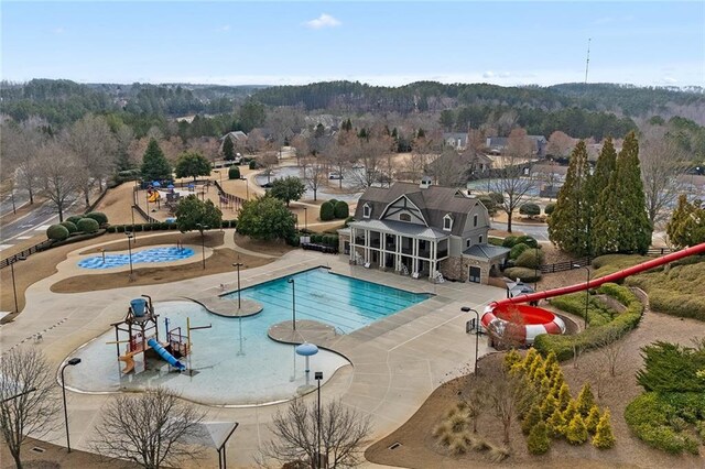 community pool featuring a patio area, fence, and a water play area