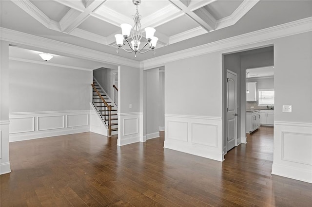 unfurnished room with an inviting chandelier, ornamental molding, wood finished floors, beamed ceiling, and stairs