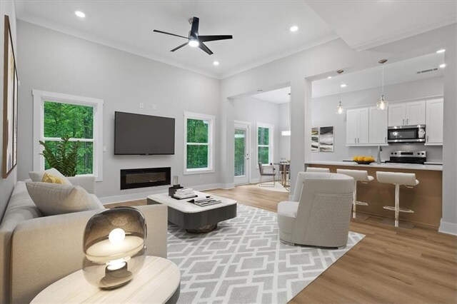 3902 Bouldercrest Rd SE, Ellenwood, GA 30294 - living room featuring a ceiling fan, crown molding, light wood-type flooring, a glass covered fireplace, and recessed lighting