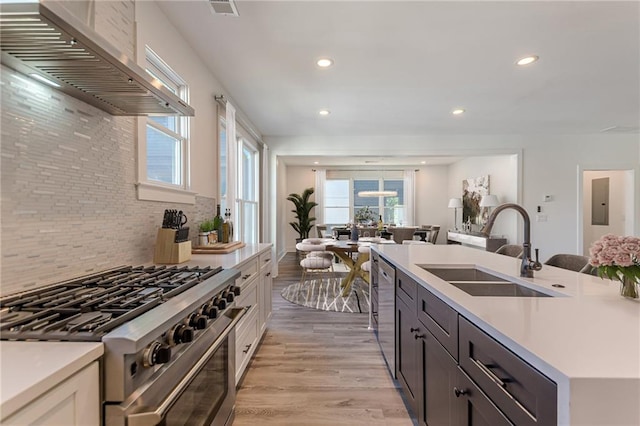 668 Liella Park SE, Atlanta, GA 30312 - kitchen with wall chimney range hood, backsplash, sink, light hardwood / wood-style floors, and stainless steel appliances