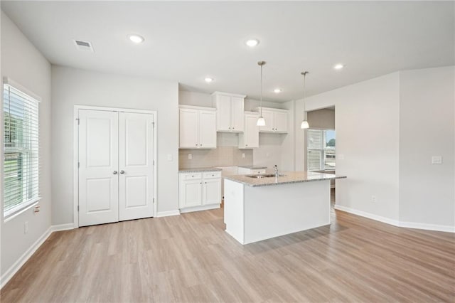 350 Lanier Cir, Woodstock, GA 30189 - kitchen with light wood-style floors, white cabinetry, a kitchen island with sink, light stone counters, and recessed lighting