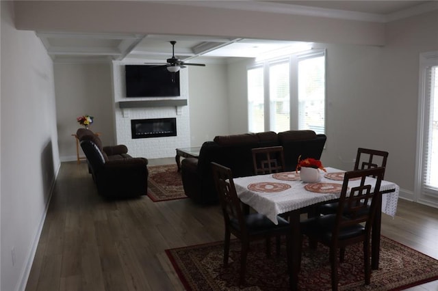 dining room featuring ceiling fan, a fireplace, beam ceiling, wood-type flooring, and coffered ceiling