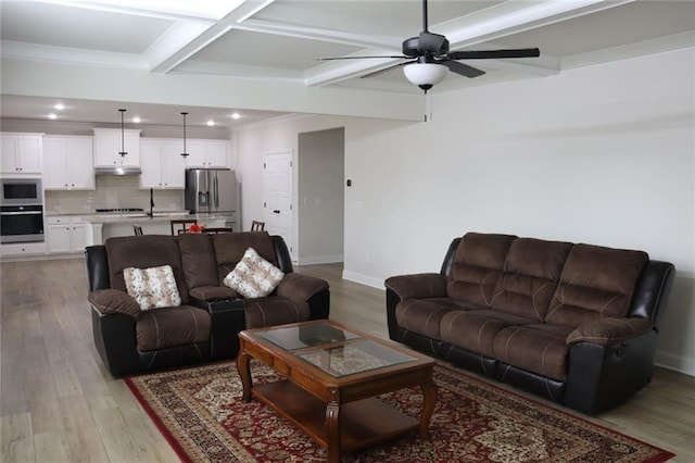 living room with coffered ceiling, ceiling fan, light wood-type flooring, crown molding, and beam ceiling