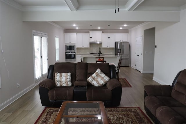 living room with beam ceiling, wood-type flooring, and ornamental molding