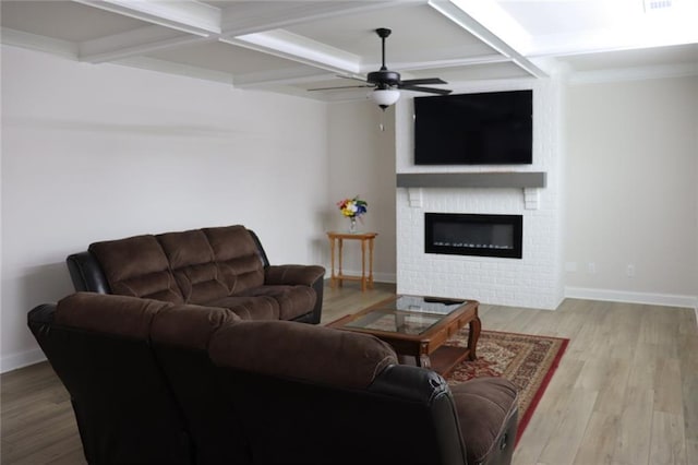 living room with coffered ceiling, ceiling fan, a fireplace, light hardwood / wood-style flooring, and beamed ceiling