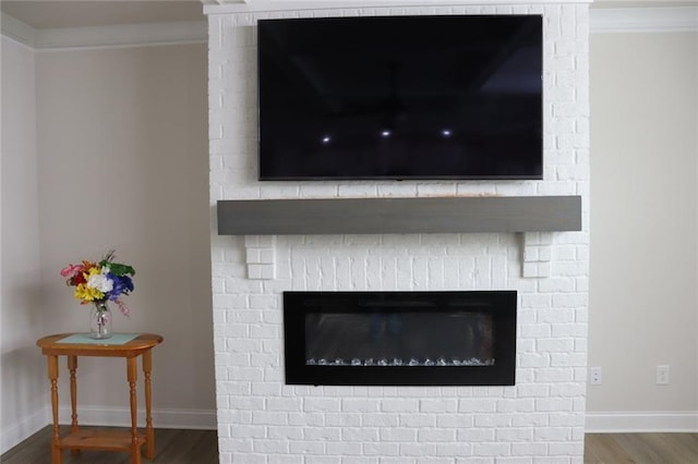 interior details with a brick fireplace, ornamental molding, and hardwood / wood-style floors