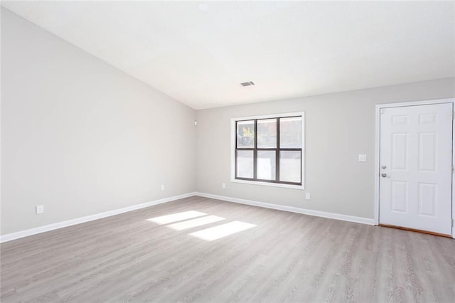 unfurnished living room with lofted ceiling, a stone fireplace, and light wood-type flooring