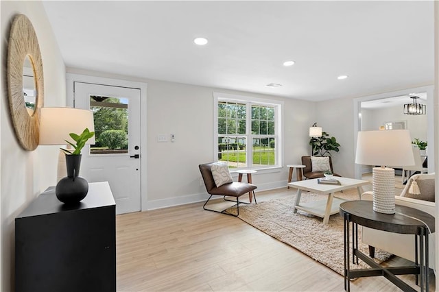 living room featuring light hardwood / wood-style flooring, plenty of natural light, and a notable chandelier