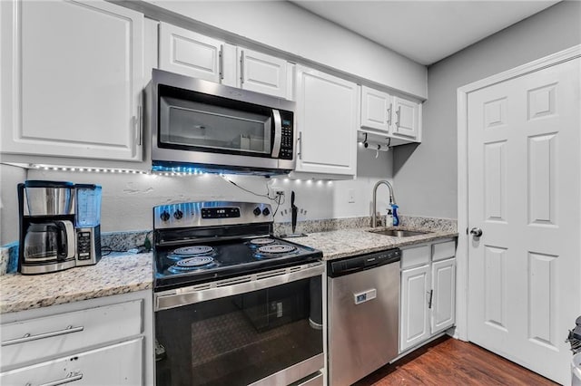 kitchen featuring sink, light stone counters, dark hardwood / wood-style flooring, white cabinets, and appliances with stainless steel finishes