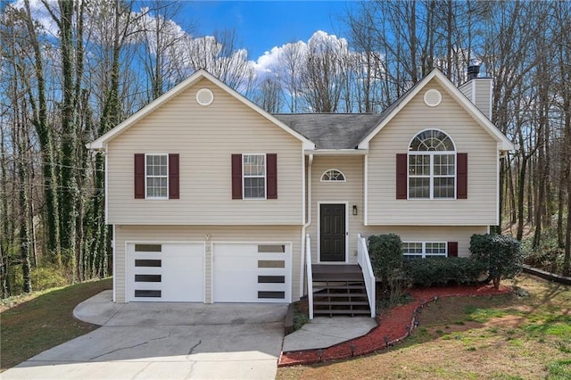 bi-level home featuring concrete driveway, a chimney, and an attached garage