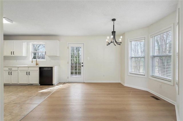 unfurnished dining area with visible vents, a sink, light wood-style floors, an inviting chandelier, and baseboards