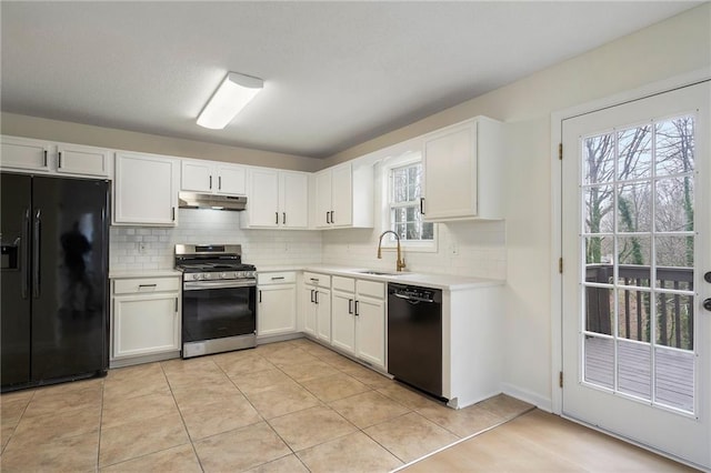 kitchen with black appliances, under cabinet range hood, a sink, light countertops, and decorative backsplash