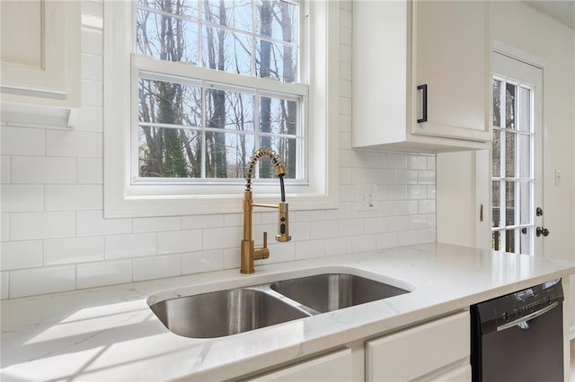 kitchen with a sink, backsplash, black dishwasher, and a healthy amount of sunlight