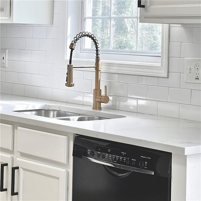 interior details with a sink, tasteful backsplash, black dishwasher, and white cabinets