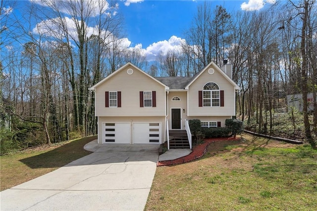 split foyer home with a garage, a chimney, concrete driveway, and a front yard