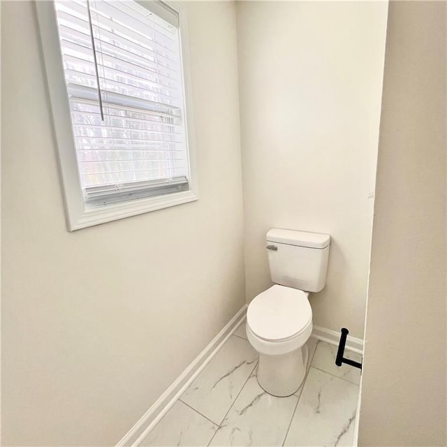 bathroom with toilet, baseboards, and marble finish floor