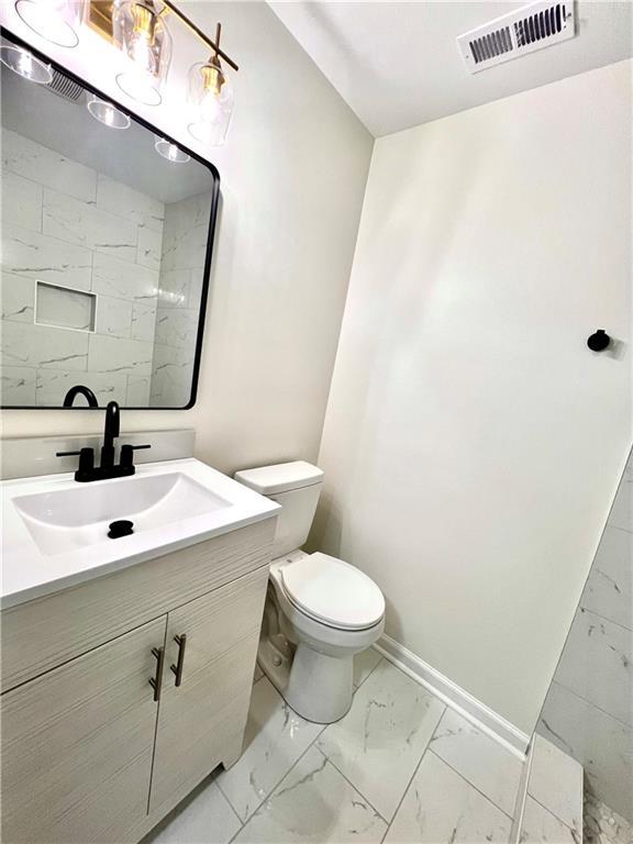 bathroom featuring visible vents, baseboards, toilet, marble finish floor, and vanity