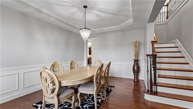 dining space with a chandelier, stairway, a tray ceiling, ornamental molding, and dark wood-style flooring