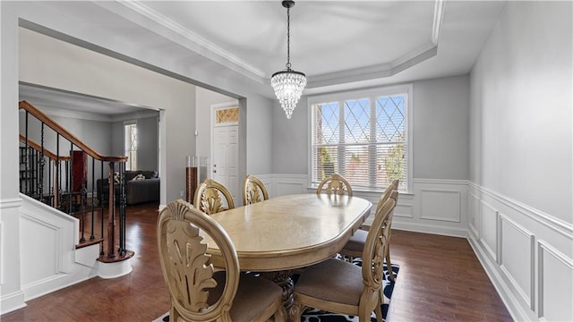 dining room with stairway, an inviting chandelier, ornamental molding, dark wood-type flooring, and a decorative wall