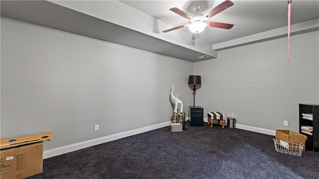 below grade area with baseboards, carpet floors, and a ceiling fan