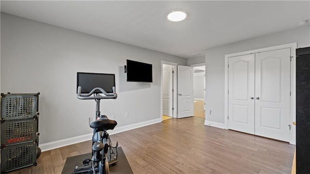 exercise room with baseboards and wood finished floors