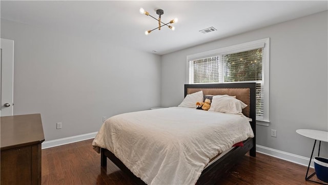 bedroom with visible vents, baseboards, wood finished floors, and a chandelier