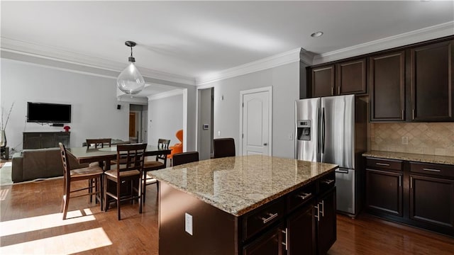 kitchen with dark wood-style flooring, hanging light fixtures, stainless steel refrigerator with ice dispenser, open floor plan, and backsplash