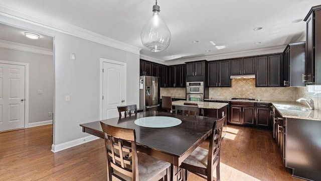 dining room featuring dark wood finished floors, crown molding, and baseboards