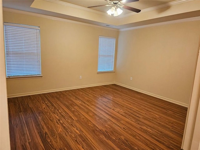 empty room featuring dark hardwood / wood-style flooring, ornamental molding, and a tray ceiling