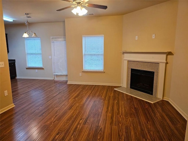 unfurnished living room featuring plenty of natural light, dark wood-type flooring, and ceiling fan with notable chandelier