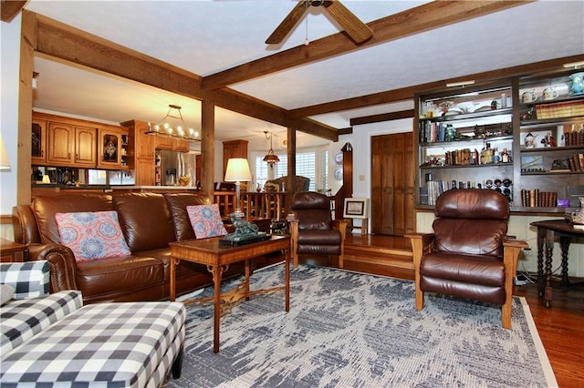 living area featuring ceiling fan with notable chandelier, beamed ceiling, and wood finished floors