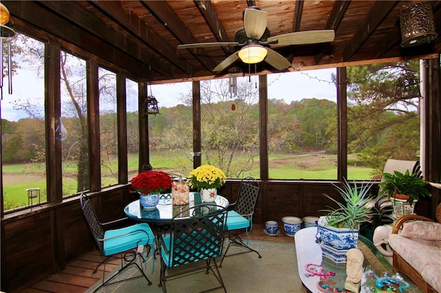 sunroom featuring a view of trees, wood ceiling, and a ceiling fan