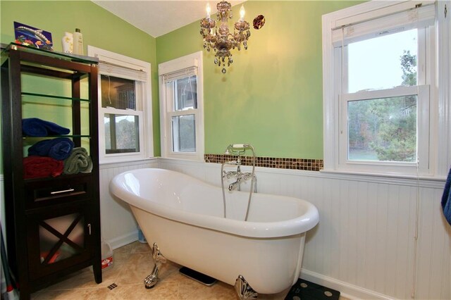 bathroom featuring tile patterned floors, a soaking tub, and wainscoting