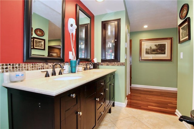 full bath with a sink, baseboards, double vanity, and tile patterned floors