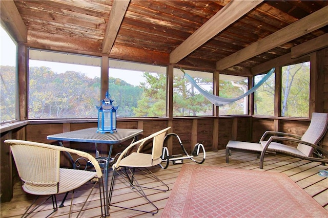 sunroom featuring beam ceiling, wood ceiling, and a wooded view