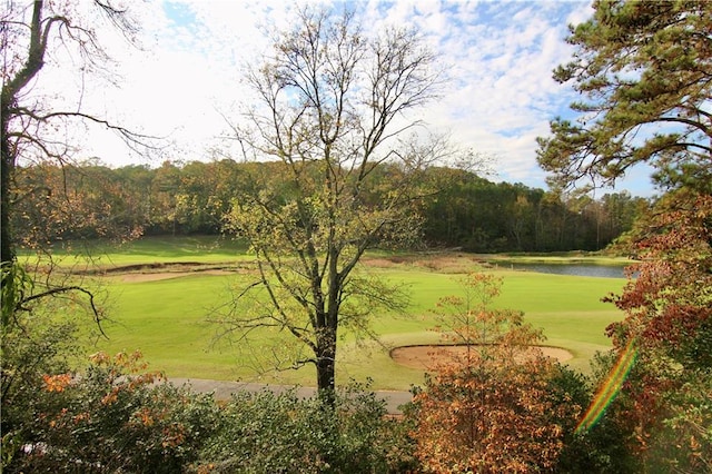 view of property's community with view of golf course, a yard, and a water view