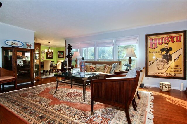 living room with baseboards, crown molding, an inviting chandelier, and wood finished floors