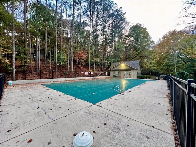 view of swimming pool featuring a fenced in pool, fence, an exterior structure, an outdoor structure, and a patio area