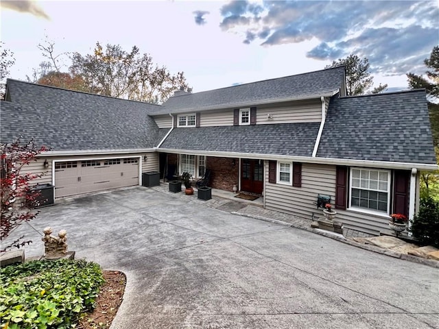 view of front of home with an attached garage, driveway, and a shingled roof