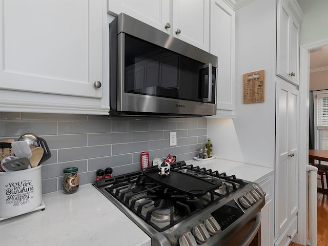 kitchen featuring white cabinetry, light stone counters, stainless steel appliances, hardwood / wood-style floors, and decorative backsplash