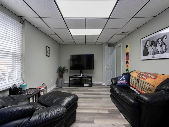 living room with a drop ceiling and light wood-type flooring