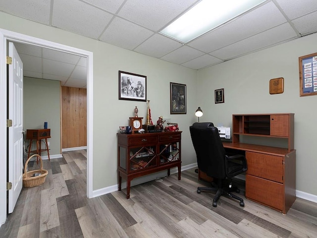 home office with light hardwood / wood-style floors and a drop ceiling