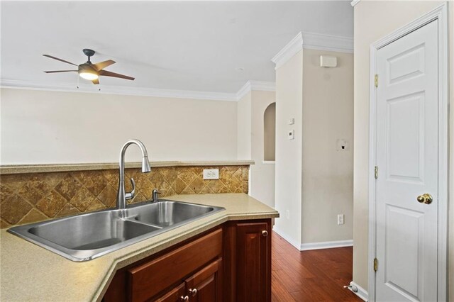 kitchen featuring dark hardwood / wood-style flooring, sink, backsplash, crown molding, and ceiling fan