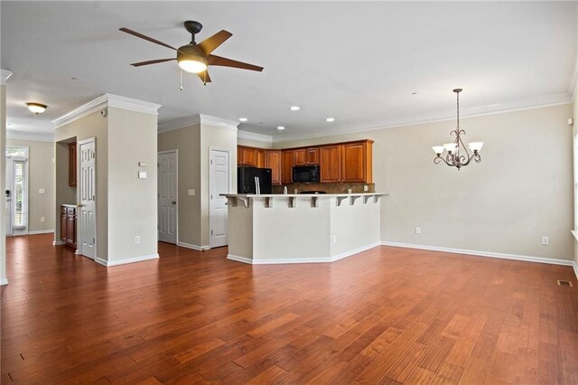 unfurnished living room featuring ceiling fan with notable chandelier, dark hardwood / wood-style floors, and crown molding