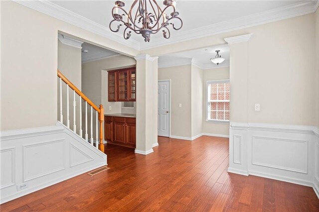 interior space featuring ornate columns, a notable chandelier, dark hardwood / wood-style floors, and ornamental molding