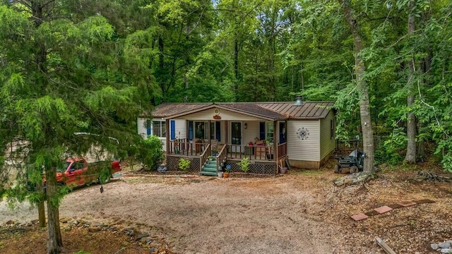 131 W Blue Branch Rd, Eatonton, GA 31024 - view of front of house featuring covered porch, a standing seam roof, a metal roof, and a forest view