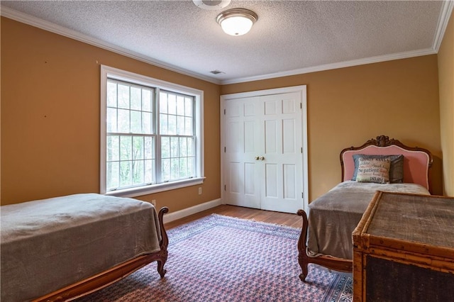 bedroom featuring a closet, hardwood / wood-style floors, a textured ceiling, and ornamental molding